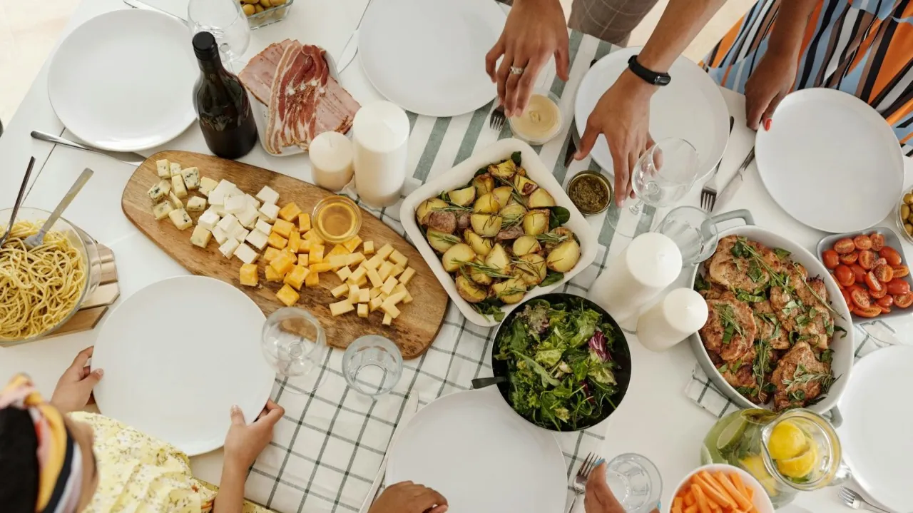Overhead view of people sharing a table of salads, pasta, cheese and roasted dishes.